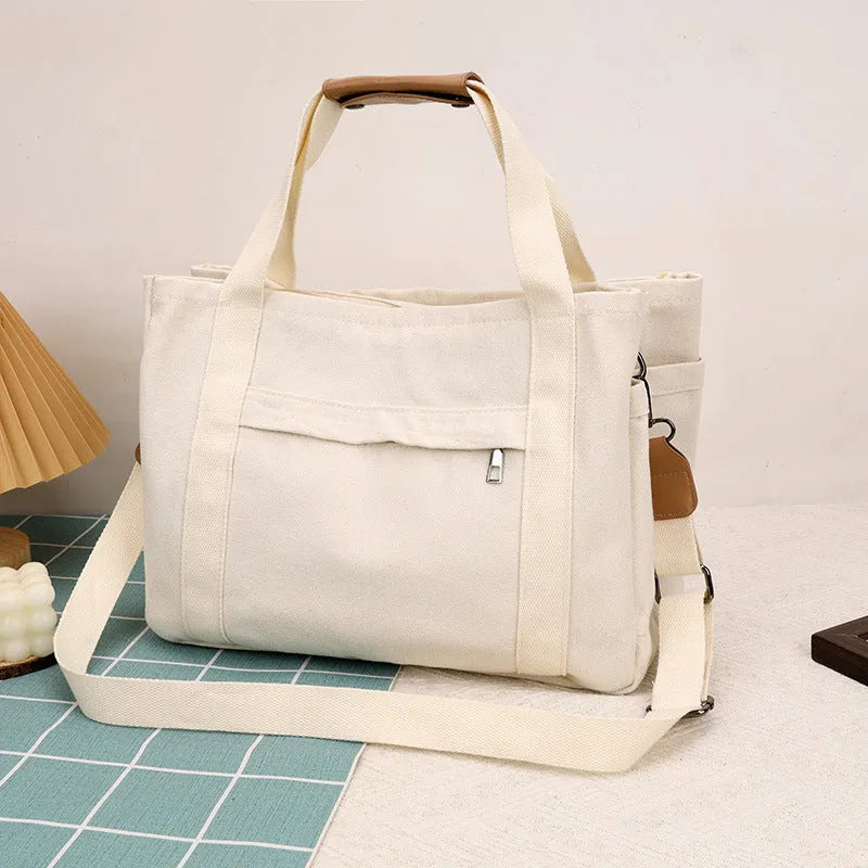 Horizontal square canvas tote bag with side zipper compartments and internal organisation pockets