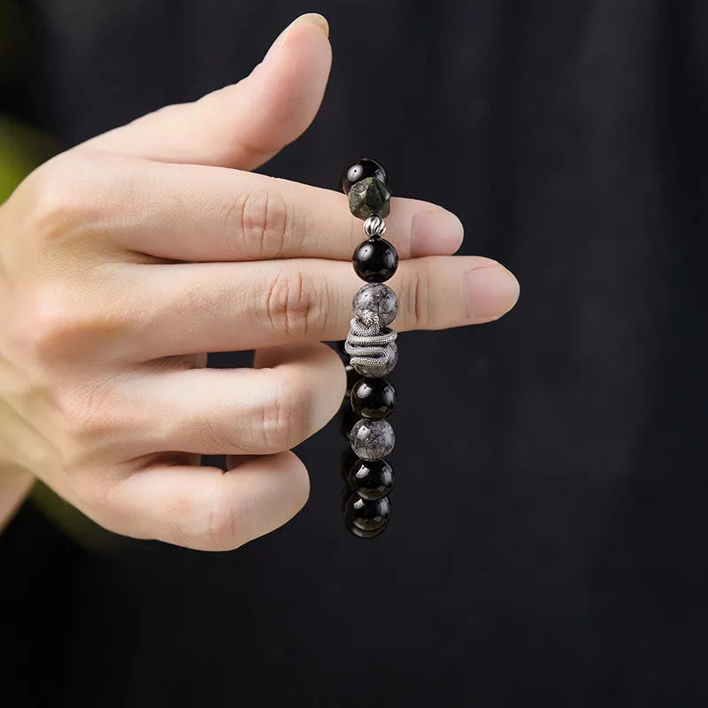Men's retro snake bracelet in sterling silver with a large black obsidian stone on a dark background.
