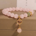 Pink crystal bracelet with four-leaf clover pendant and rhinestone details