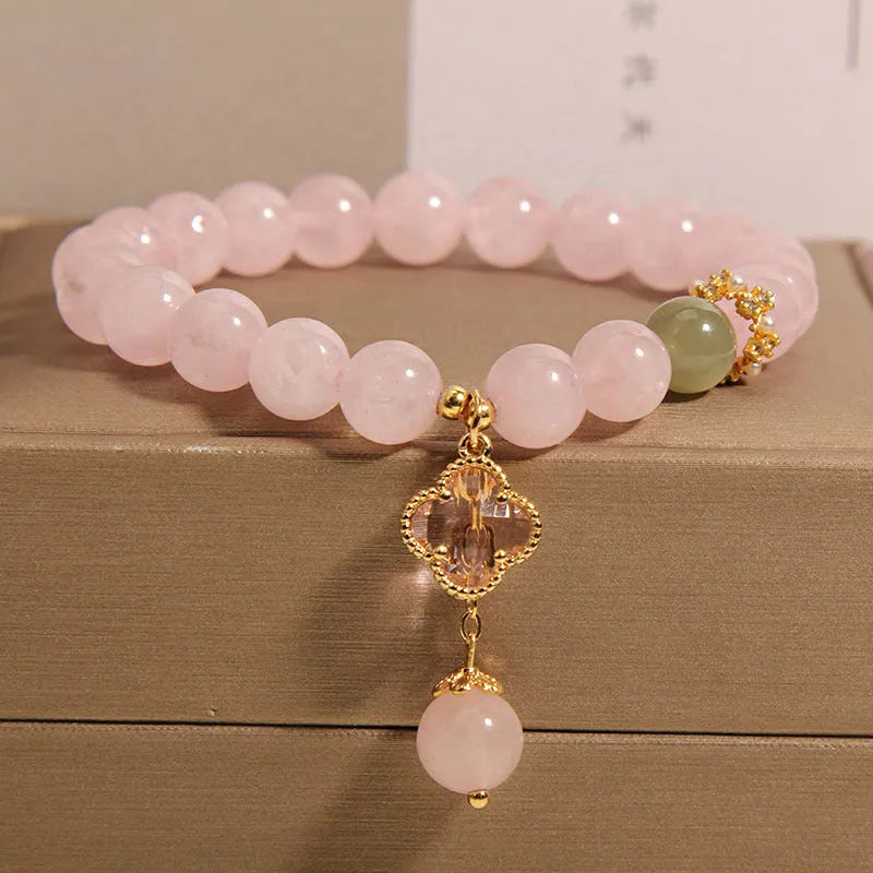 Pink crystal bracelet with four-leaf clover pendant and rhinestone details
