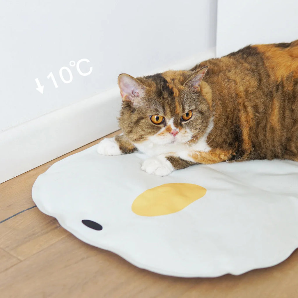Blue chick-shaped washable pet cooling mat on a wooden floor.
