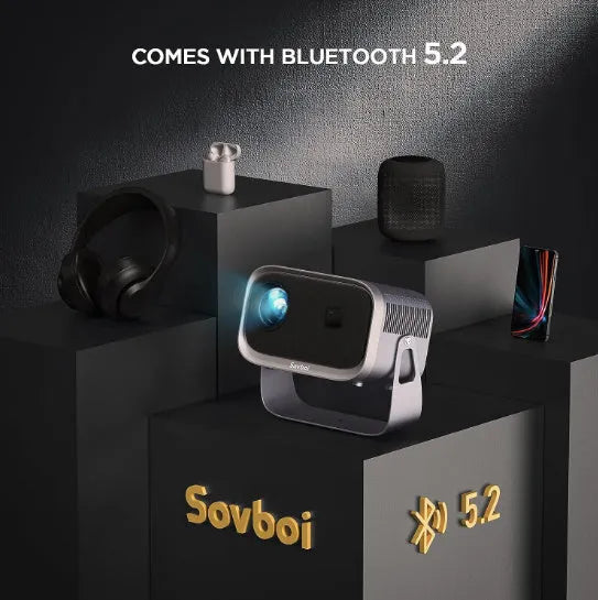 Portable Android 4K Full HD home projector with mobile phone on a table.
