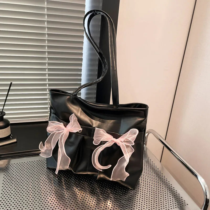 Black PU leather bow tote bag with double shoulder straps, shown with interior zipped pocket.