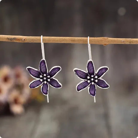 Purple flower-shaped alloy earrings with electroplated finish on white background