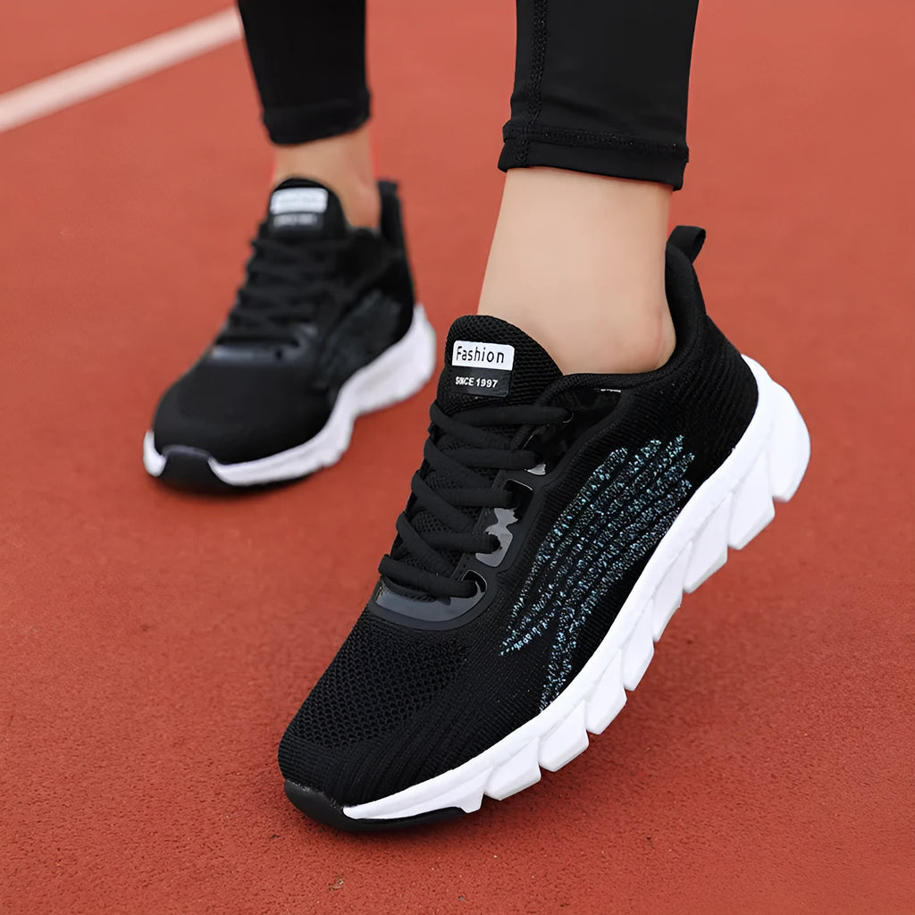 Women's low-cut black and white casual running sneakers with cross-strap detail and a lightweight MD sole.