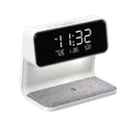 White bedside lamp with integrated wireless charging pad, LCD alarm clock screen, and touch-sensitive dimming controls.
