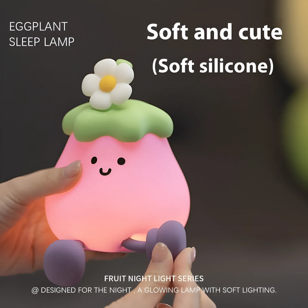 Cartoon-shaped eggplant night lamp glowing with soft yellow light on a table.
