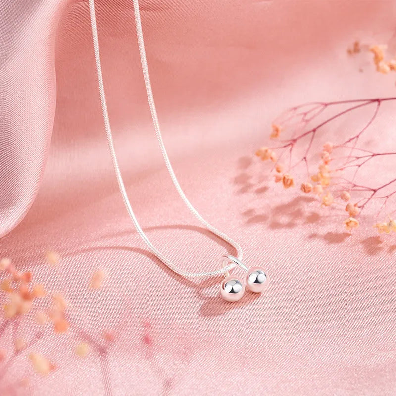 Silver cherry necklace with adjustable snake bone chain and detailed fruit pendant on a model