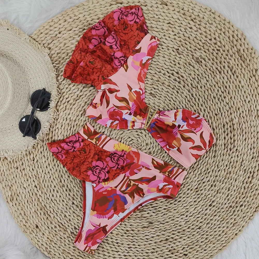 Pink women's one-shoulder ruffled bikini with red flower print and high-waist briefs.