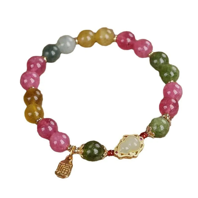 Close-up of a women's bracelet with a colourful tourmaline gourd charm and electroplated floral links.