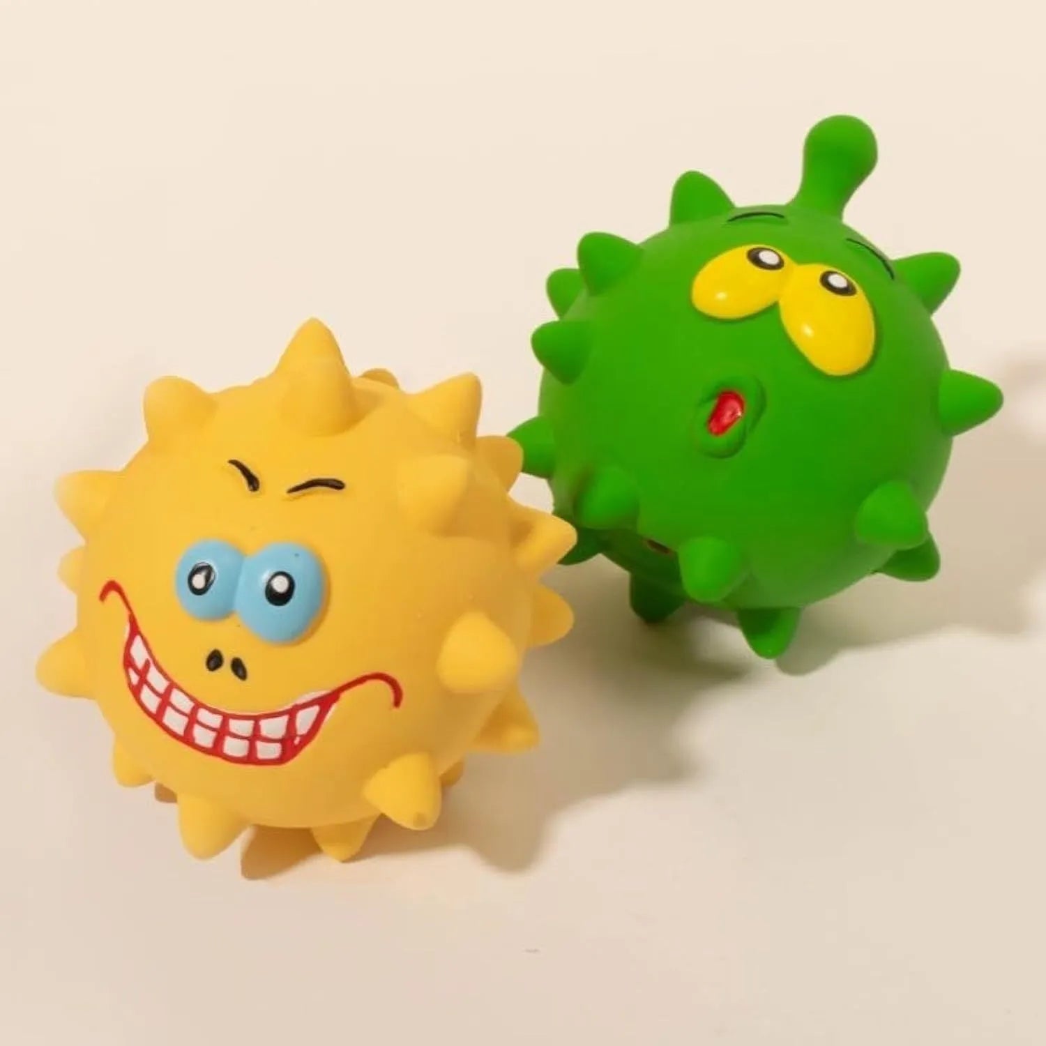 Four colourful squeaky dog balls with cute faces, showing textured surface for dental cleaning, natural latex construction