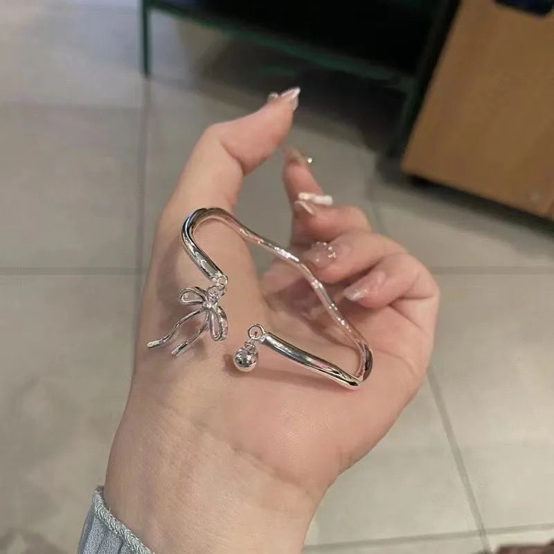 Silver adjustable bow bracelet with zinc alloy construction and electroplated finish on wrist
