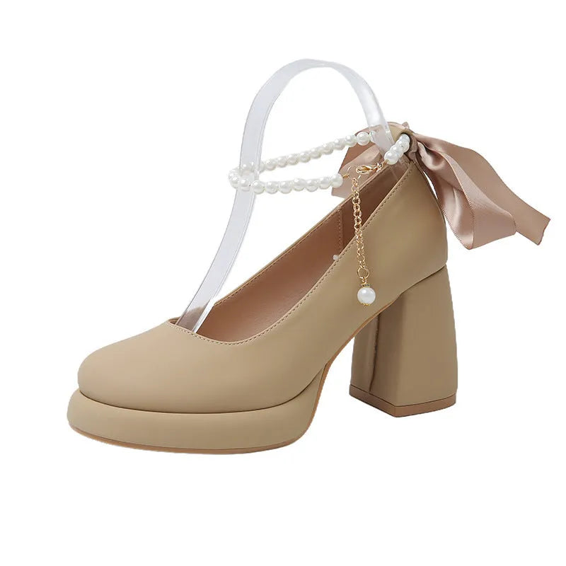 Beige women's Mary Jane shoes with a chunky heel, round toe, and pearl-decorated ankle strap buckle on a white background.