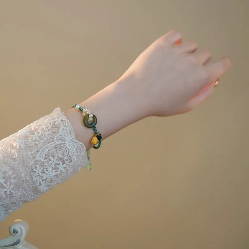 Close-up of a hand-woven flexible wire watch band with a pearl peace buckle closure.