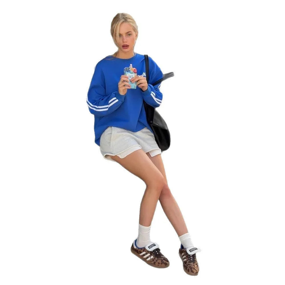 Blue cotton sweater with vintage stripes, loose round neck, and long sleeves laid flat.
