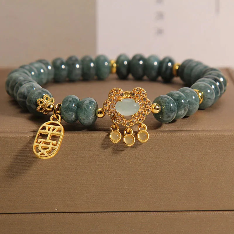Close-up of a women's bracelet with natural emerald green jade abacus beads and a metallic alloy safety lock clasp.