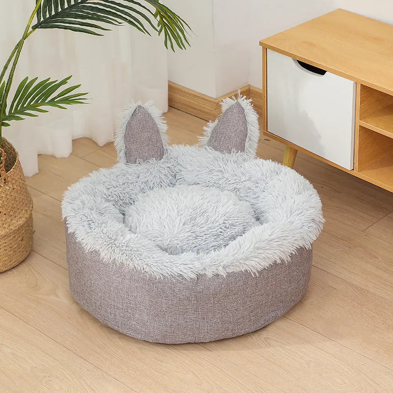 A round soft grey faux fur plush pet bed for cats or small dogs on a wooden floor.