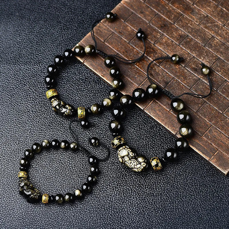 Hand-woven Golden Obsidian Pi Xiu bracelet with animal charm on wrist, showing bead detail.