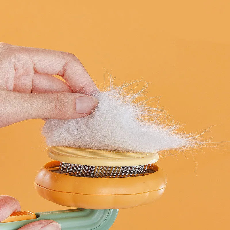 Pumpkin coloured hand-held pet grooming brush with stainless steel needles on a curved comb.