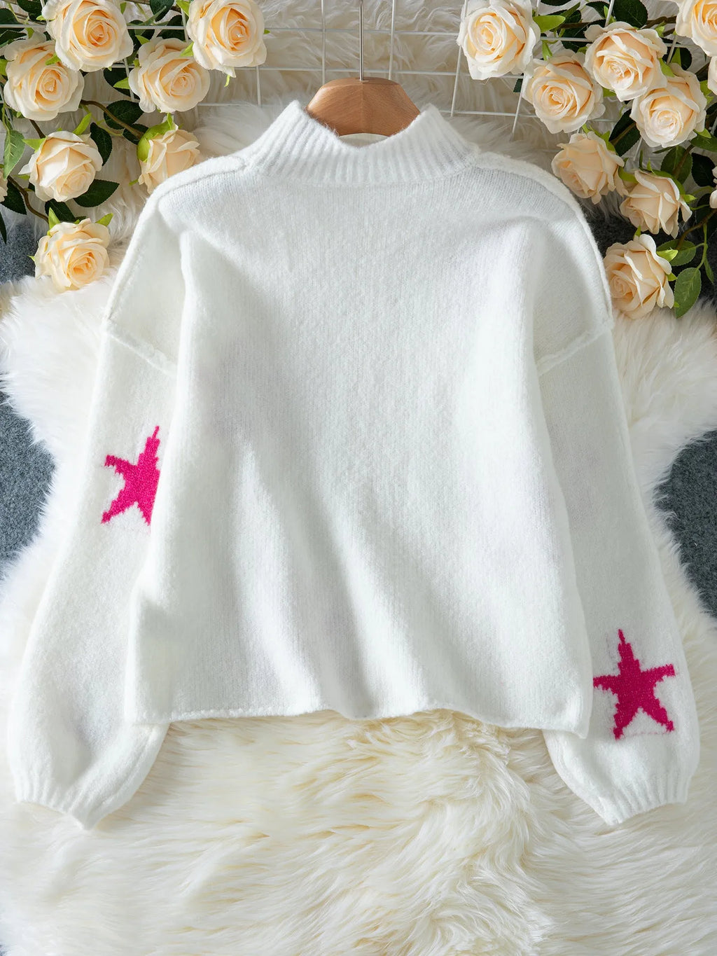 White women's turtleneck pullover sweater with a black five-pointed star pattern on the front.
