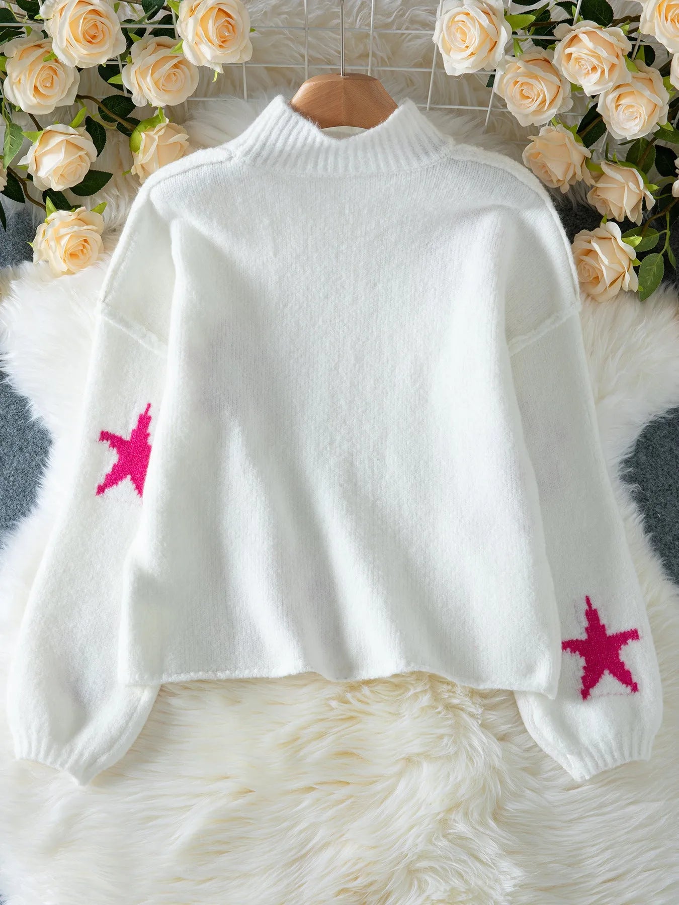 White women's turtleneck pullover sweater with a black five-pointed star pattern on the front.