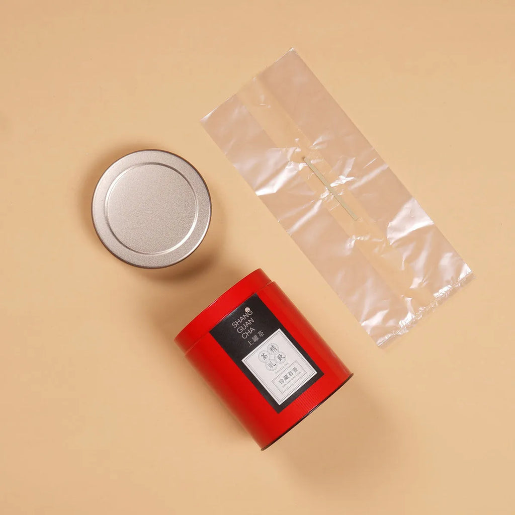Green metal tin can tea storage box with sealed lid, shown next to loose-leaf tea.