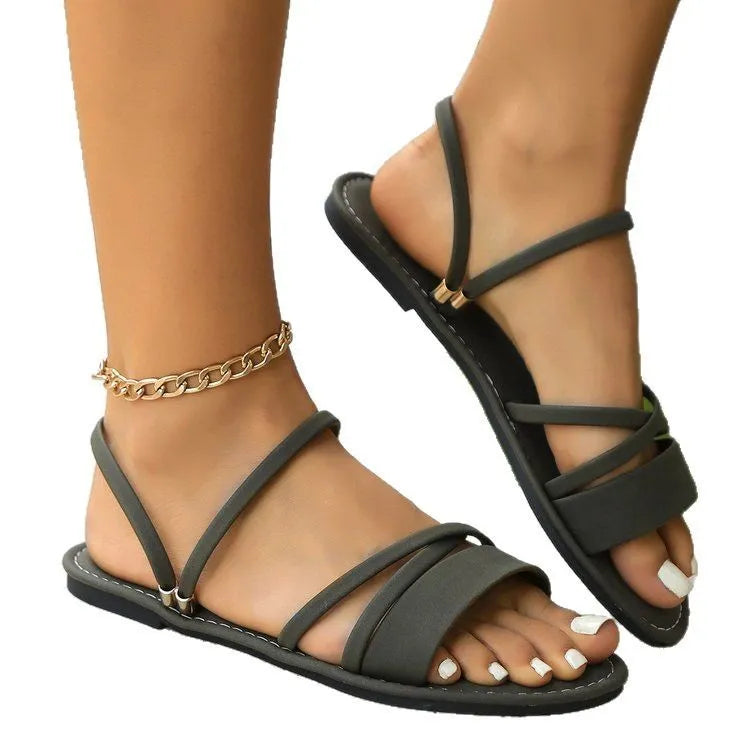 Women's plus size black sandals with flip-toe buckle and cross straps on flat rubber sole