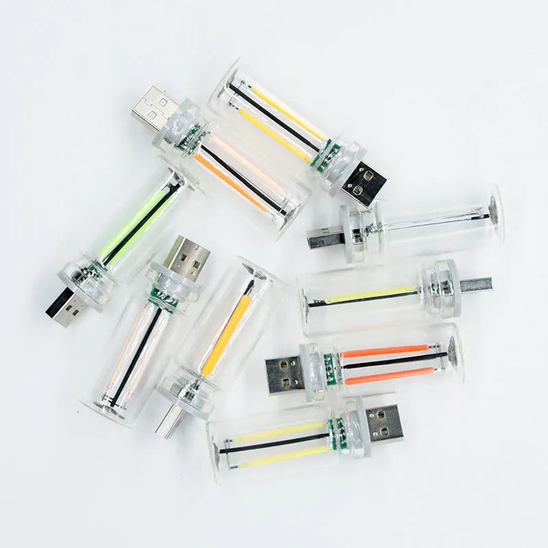 Small transparent glass USB touch night lamp with platinum base on a surface, showing warm white glow.