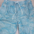 Man wearing loose blue 3D digitally printed straight-leg sports shorts on a summer day.
