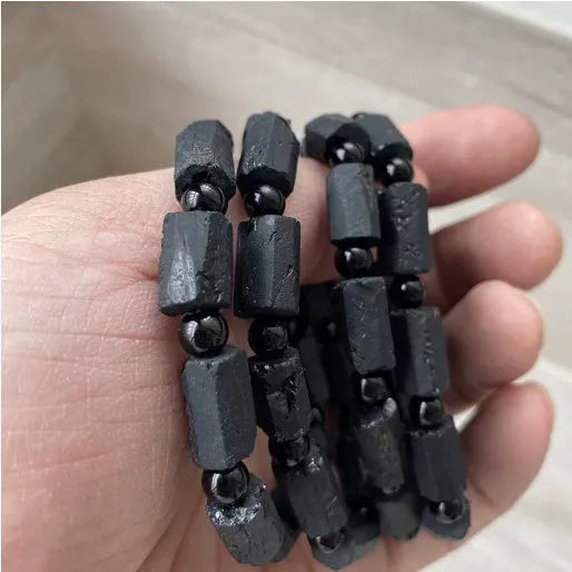 Unisex black tourmaline rough stone bracelet on wrist, showing natural texture and 10mm band width.