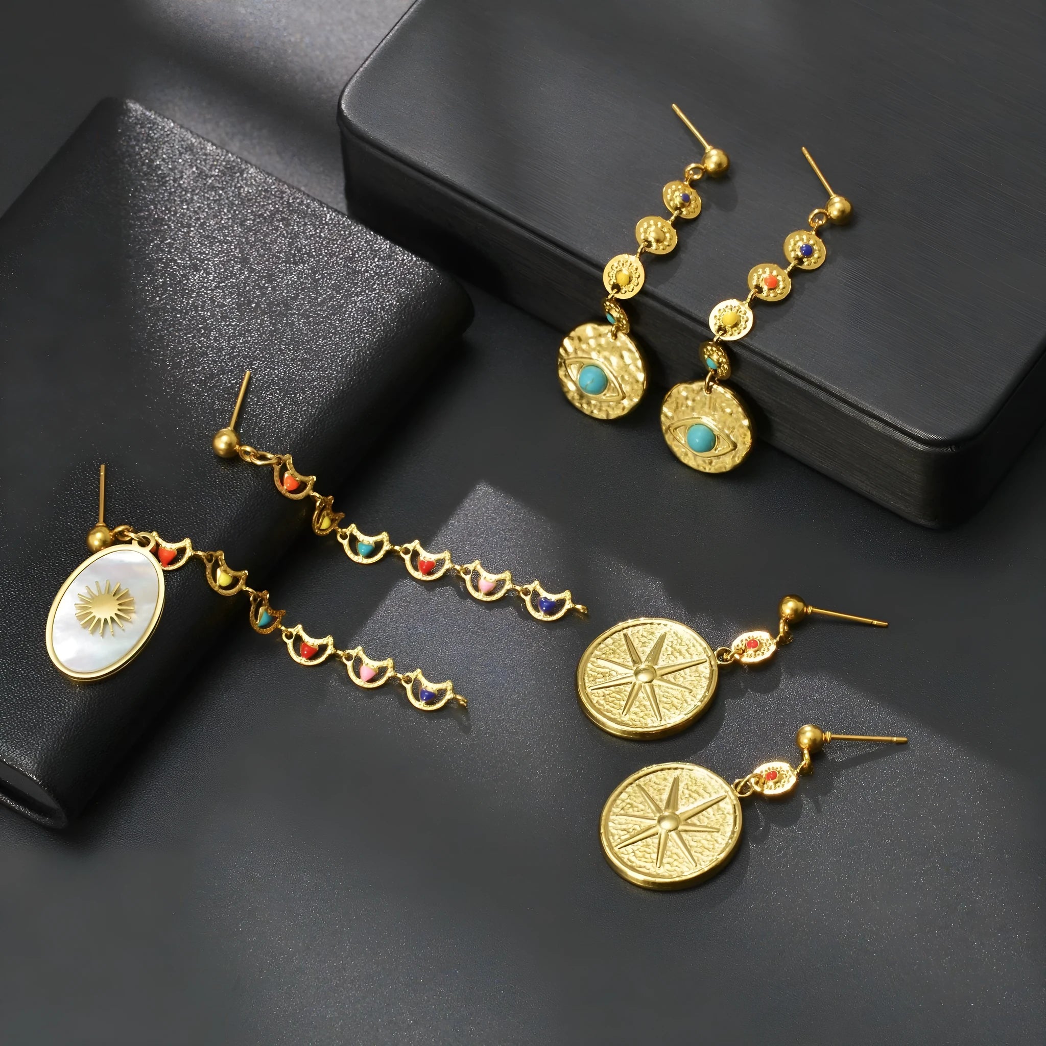 Three pairs of geometric stainless steel earrings showing Eight Awn Star, Eye, and Shell Sun designs.