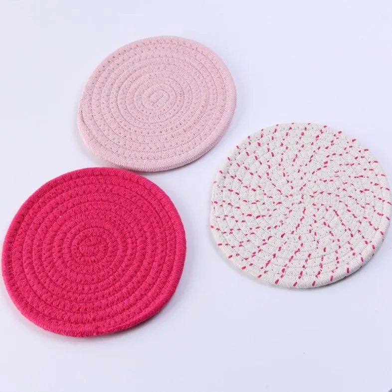 Set of three round grey cotton cord coasters on a wooden table