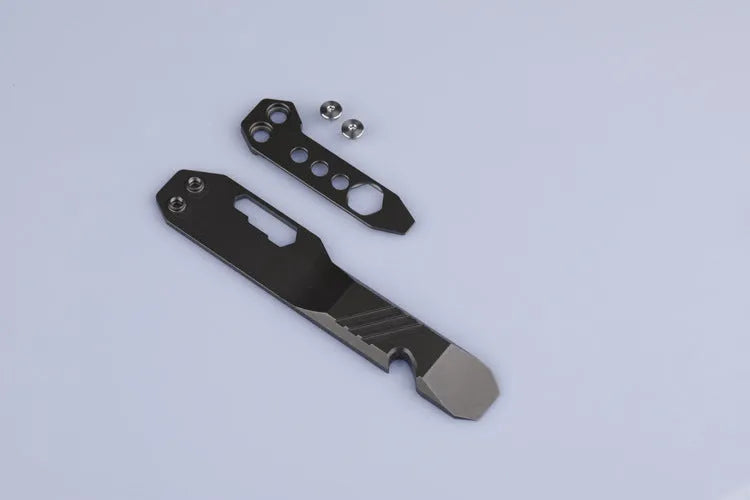 Titanium multi-function crowbar tool with screwdriver tip and bottle opener, shown in stone wash and gun grey finishes.