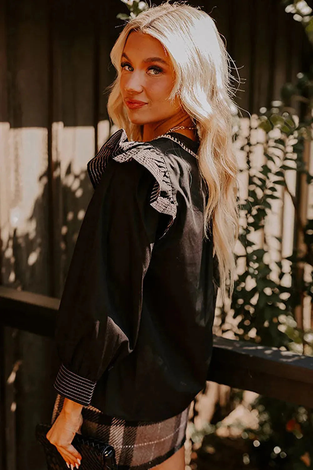Black women's blouse with V-neck, contrast stitching, and three-quarter length ruffle sleeves