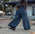 Men's grey pleated wide-leg trousers with an elasticated drawstring waistband, shown on a model.