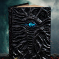Dark kraft paper A6 notebook with an embossed Cthulhu design on the cover, shown next to a gift box.