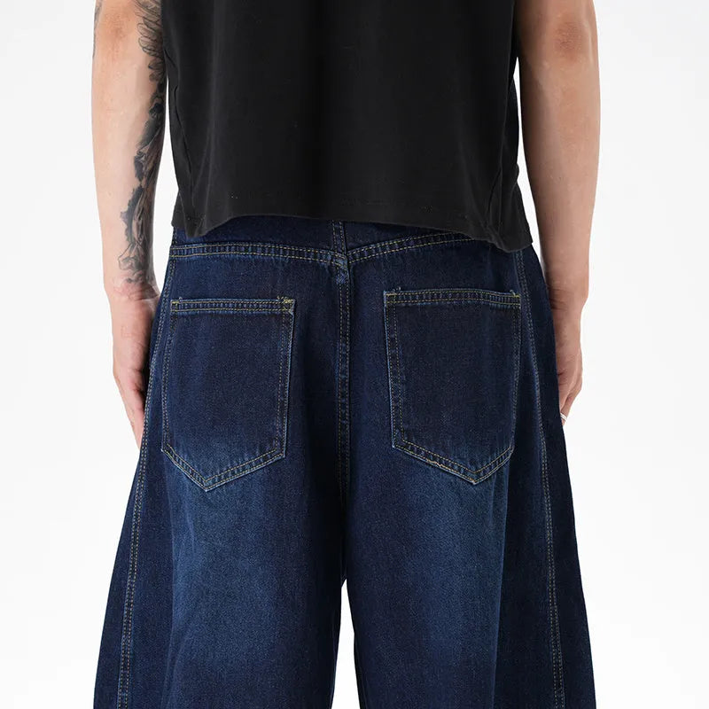 Dark blue wide leg jeans with a distressed wash and machete cut, laid flat.