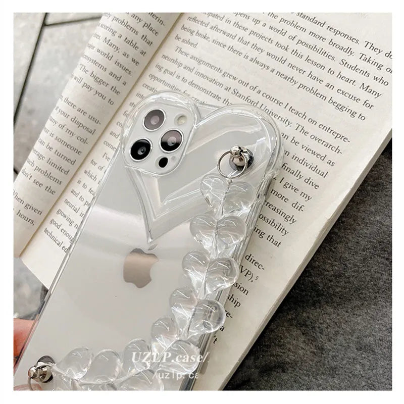 Transparent iPhone case with a soft TPU build and an integrated love heart chain, shown on a phone.