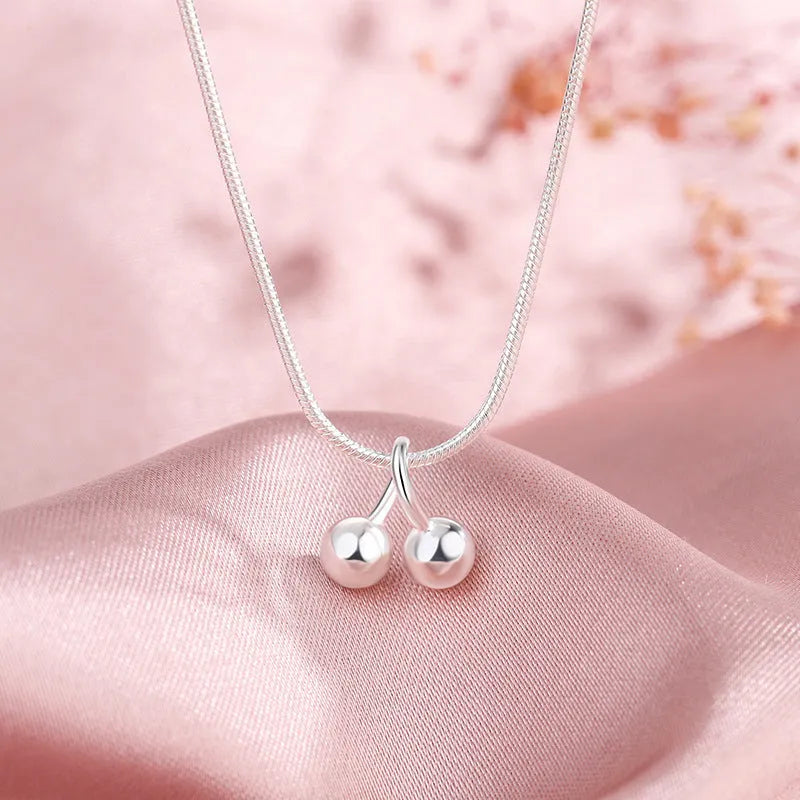 Silver cherry necklace with adjustable snake bone chain and detailed fruit pendant on a model