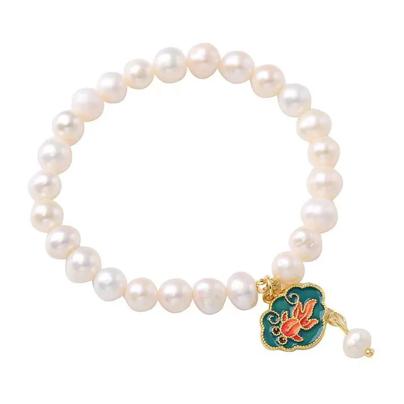 White freshwater pearl and gold electroplated lotus goldfish pendant on an antique style women's bracelet.