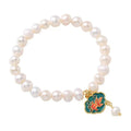 White freshwater pearl and gold electroplated lotus goldfish pendant on an antique style women's bracelet.