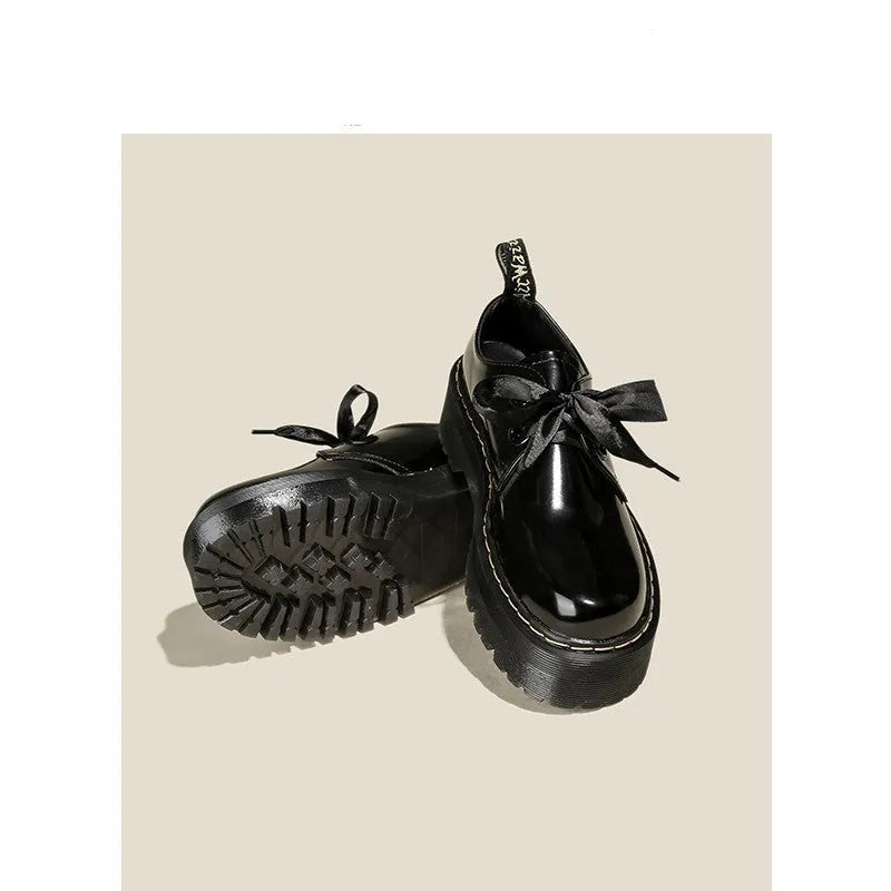 Women's black leather shoes with cross-strap design and thick TPR soles, showing ribbon detailing and lacing closure
