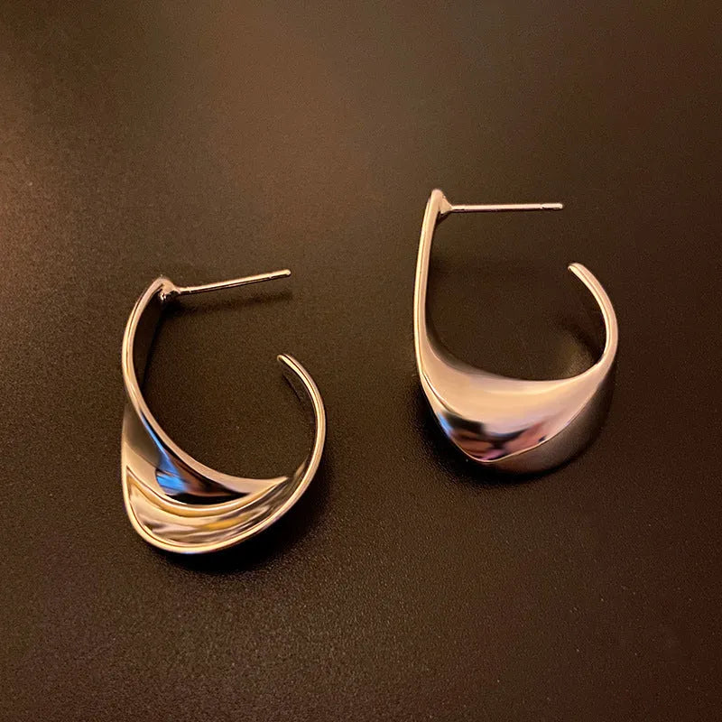 A pair of twisted geometric design metal earrings in gold or silver electroplated finish.