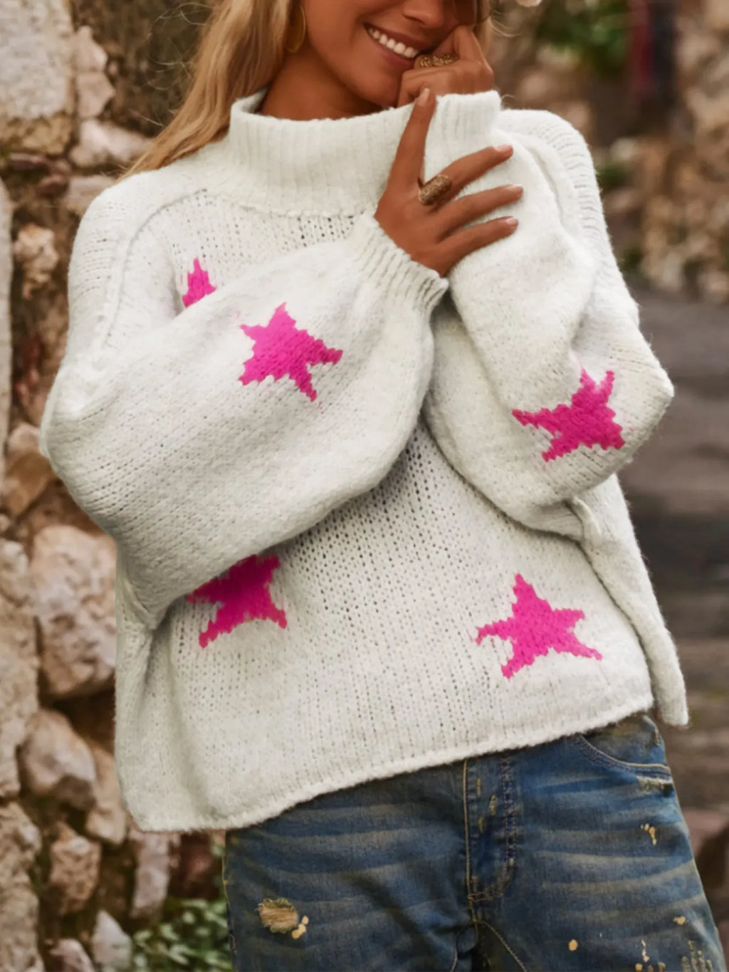 White women's turtleneck pullover sweater with a black five-pointed star pattern on the front.