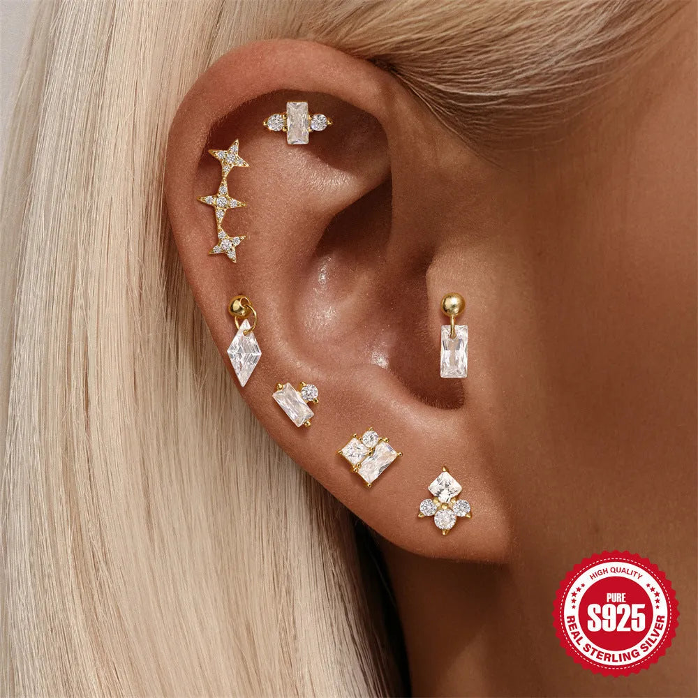 Close-up of women's sterling silver flower stud earrings with square gravel texture in a gold colour.