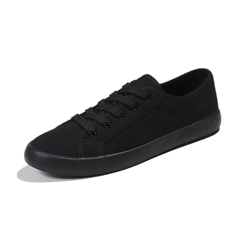 All black low-top canvas lace-up flat shoes for women with a rubber sole.