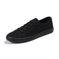 All black low-top canvas lace-up flat shoes for women with a rubber sole.