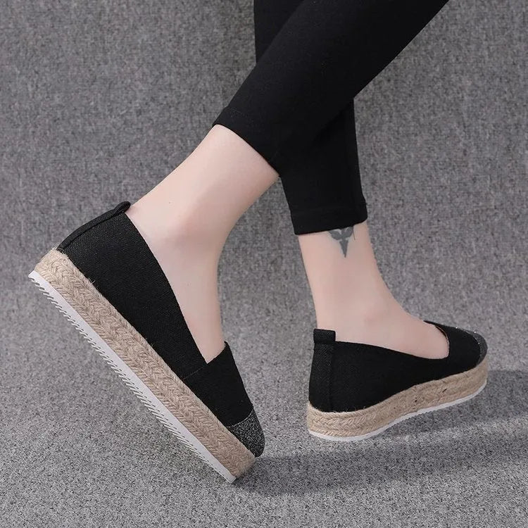 Beige and black canvas shoe covers with round toe design showing oversleeves construction