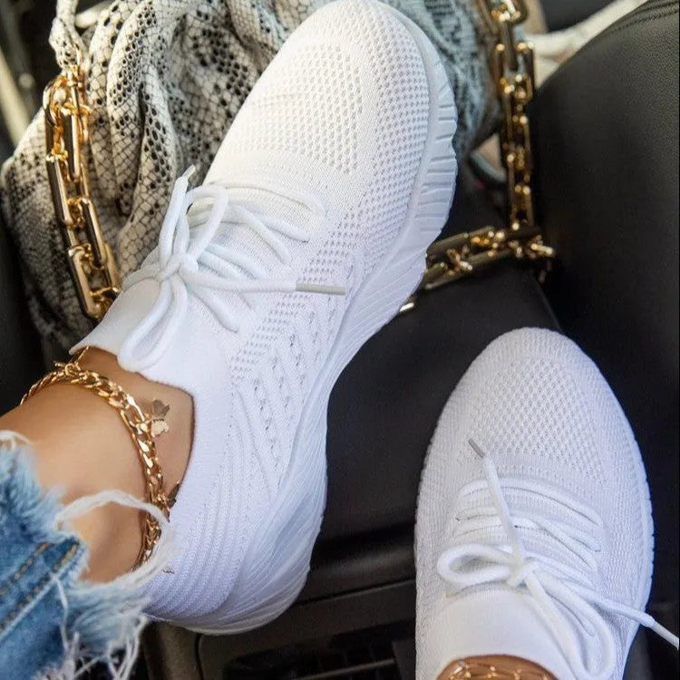 Women's white thick-sole dad sneakers on a plain background, showing the chunky sports shoe design.