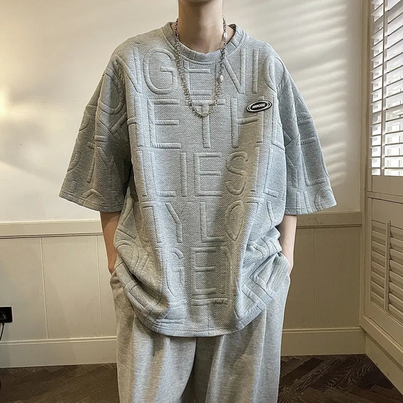 Men's grey T-shirt with raised black letters, loose fit, short sleeves, on a hanger